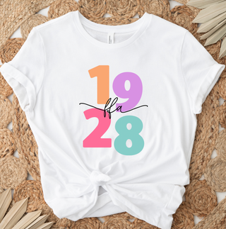 White t-shirt with colorful text design on a woven mat