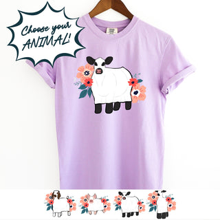 Purple t-shirt with a cow design and floral elements on a white background